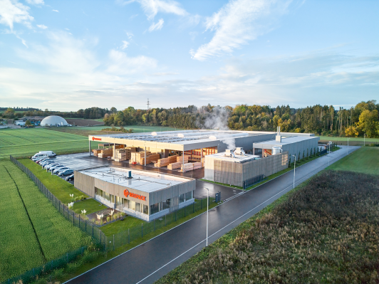 Luftaufnahme des Bropack-Neubaus mit Produktionshalle, überdachtem Lagerbereich und vorgelagertem Verwaltungsgebäude in moderner Holzbauweise in Dornhan geplant von arcplus