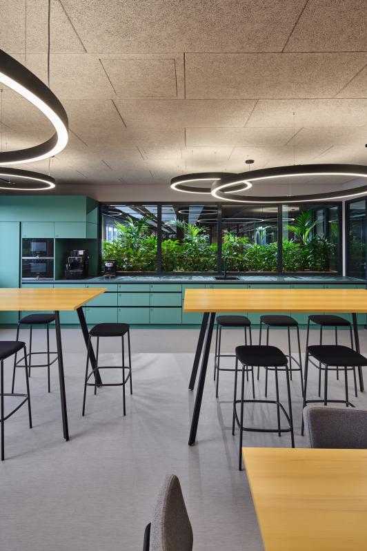 Aufenthalts- und Küchenbereich im Bürogebäude der Homag Group in Holzbronn mit begrüntem Innenraum, maßgefertigten Schreinerarbeiten und integrierter Lichtgestaltung, entworfen vom Innenarchitektenteam von arcplus Architekten