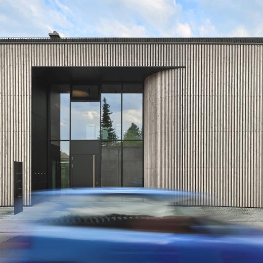 Eingangsbereich des Bürogebäudes ›Büro am Stadtbahnhof‹ mit großzügiger Glasfassade und gerundeter Fassadengeometrie, geplant und realisiert von arcplus Architekten als eigenes Büro