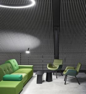 Loungebereich im Bürogebäude ›Büro am Stadtbahnhof‹ mit bewusst gesetzter Sitzmöblierung in Grüntönen, klaren Möbelkonturen und zurückhaltender Beleuchtung als Teil des innenarchitektonischen Konzepts, geplant und realisiert von arcplus 